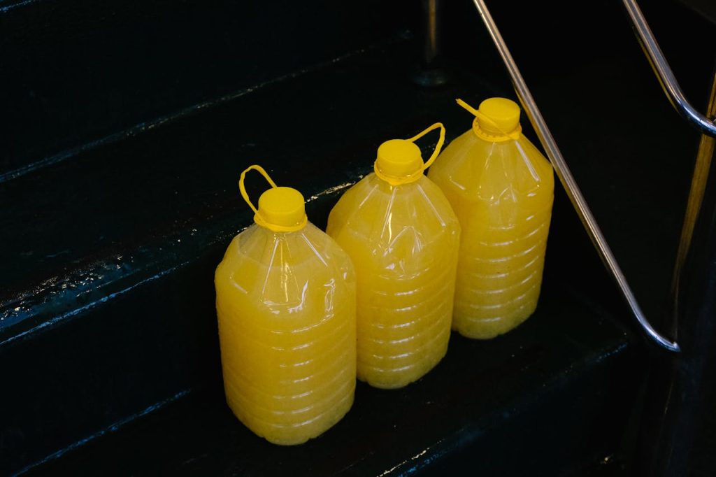 Three large yellow juice containers placed on a metal-railed staircase.
